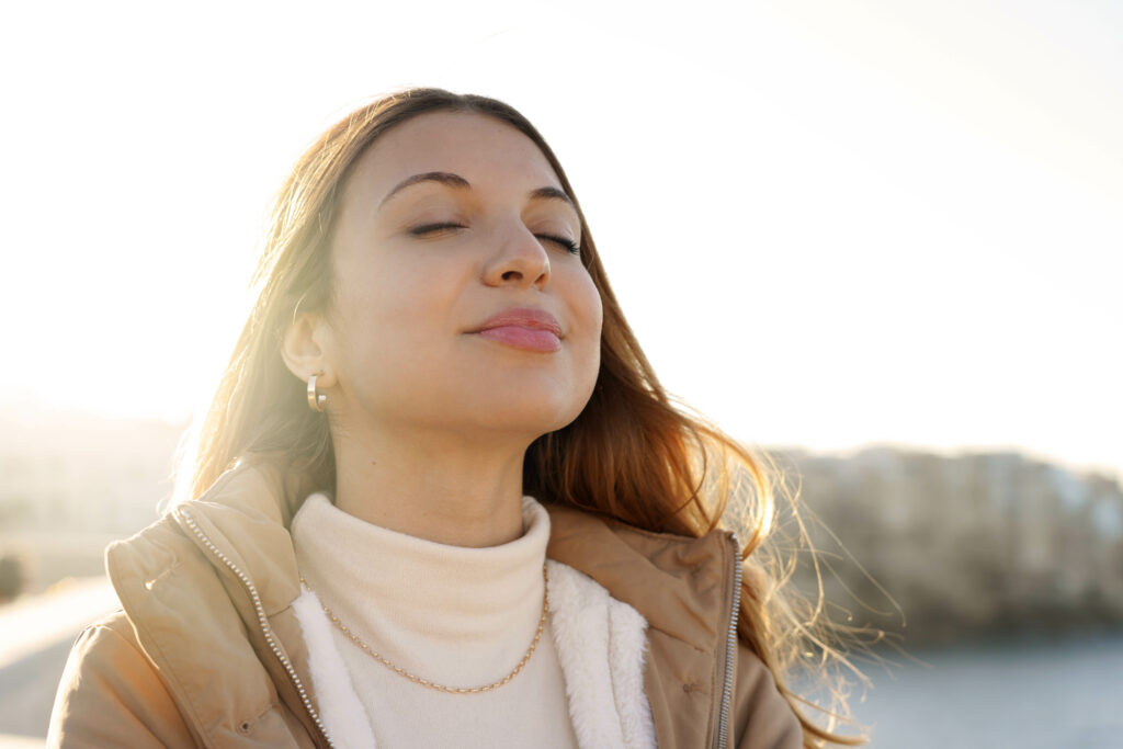Young charming woman breathing fresh air relaxing and smiling
