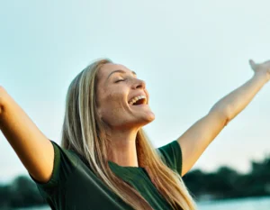 Woman smiling at the sun, celebrating her mental health.