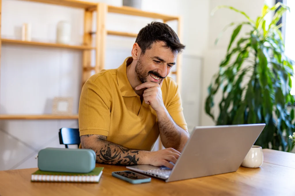 man smiling at his laptop while in group therapy