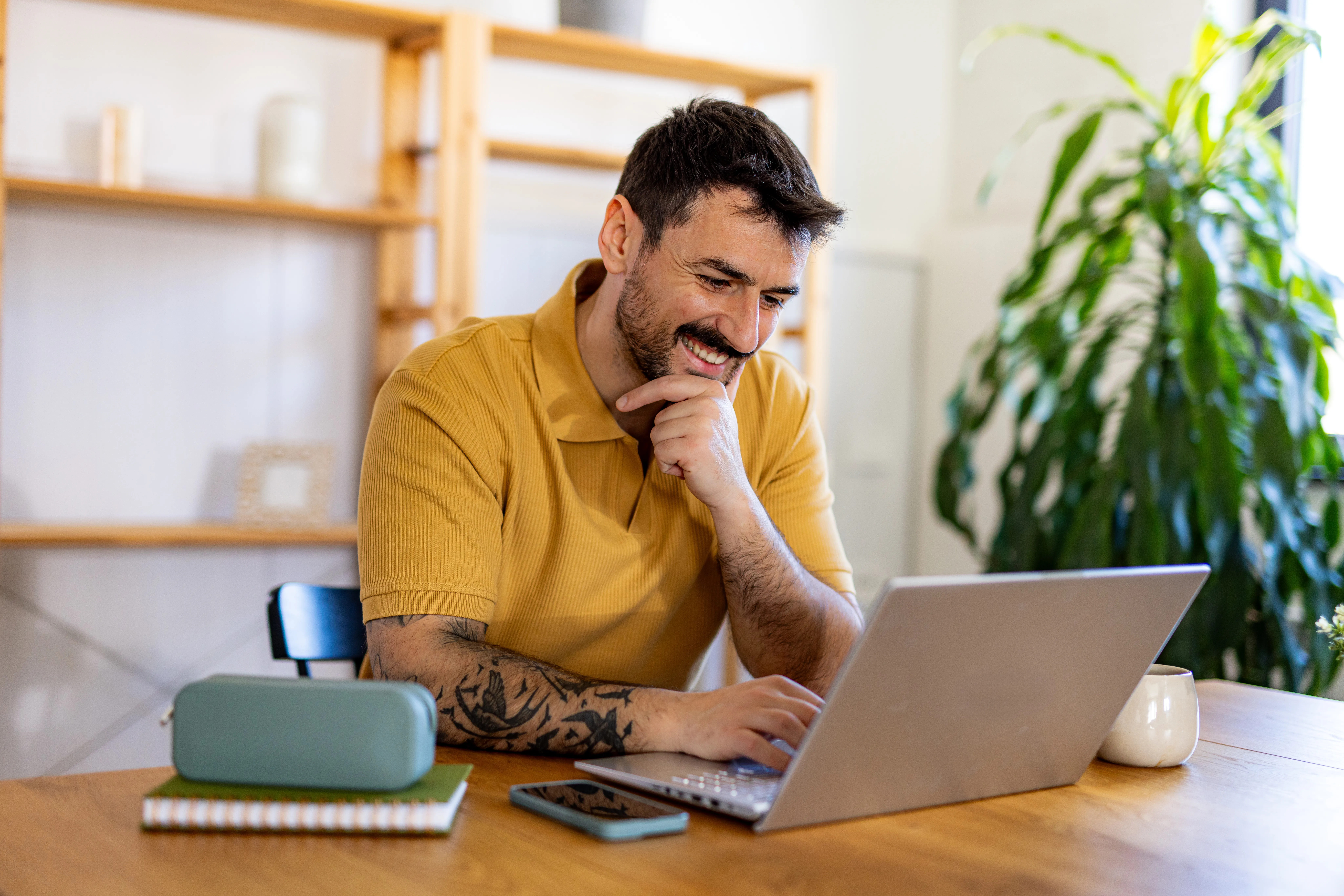 man smiling at his laptop while in group therapy