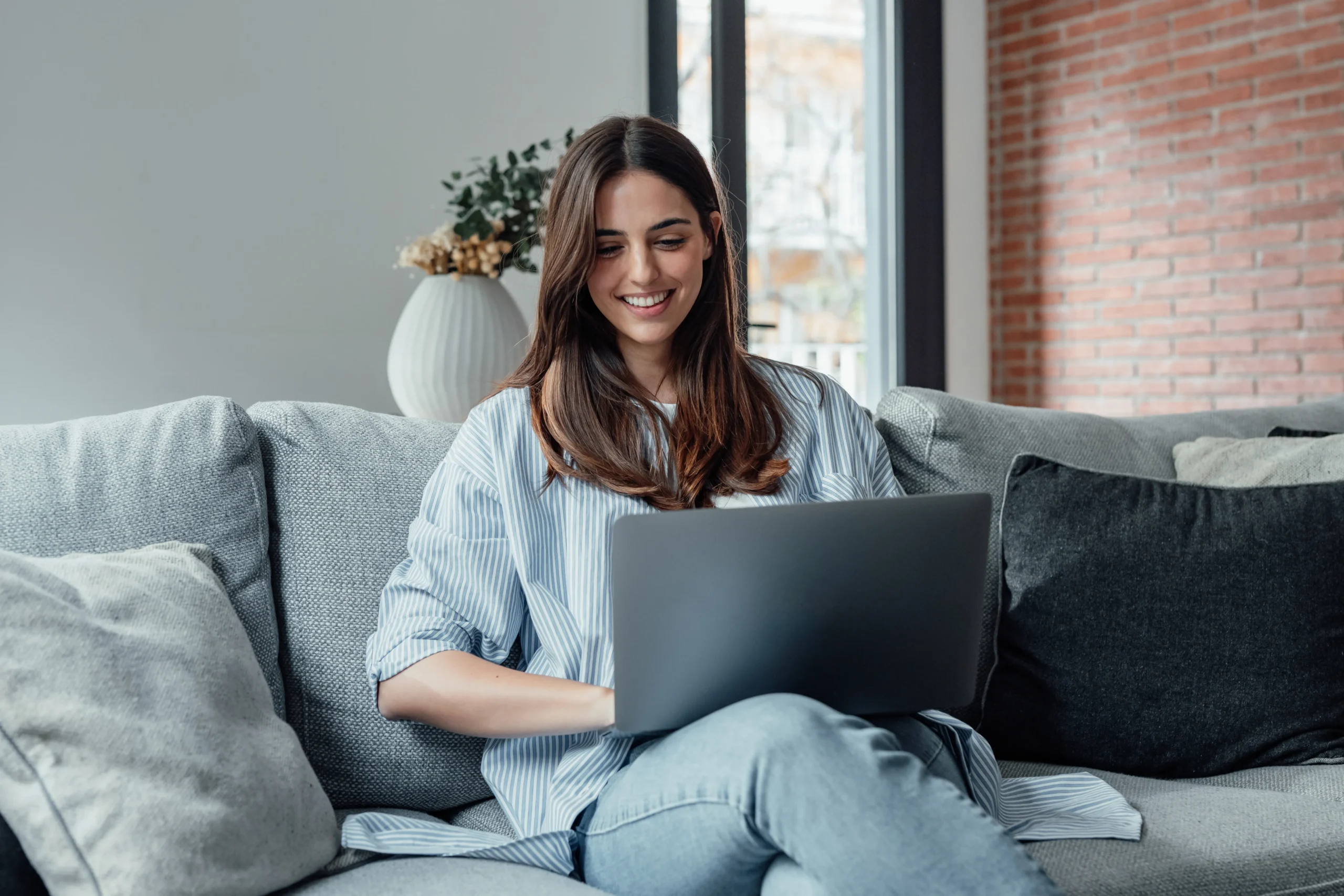 woman smiling at her laptopl while doing virtual iop from home