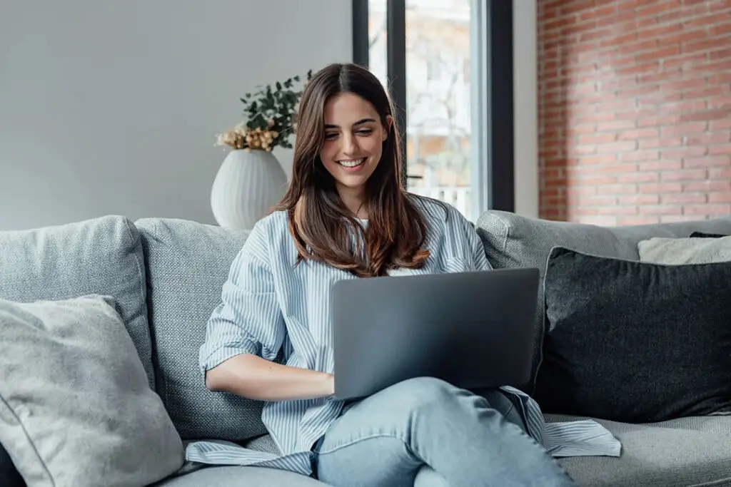 woman smiling at her laptopl while doing virtual iop from home scaled compressed,
