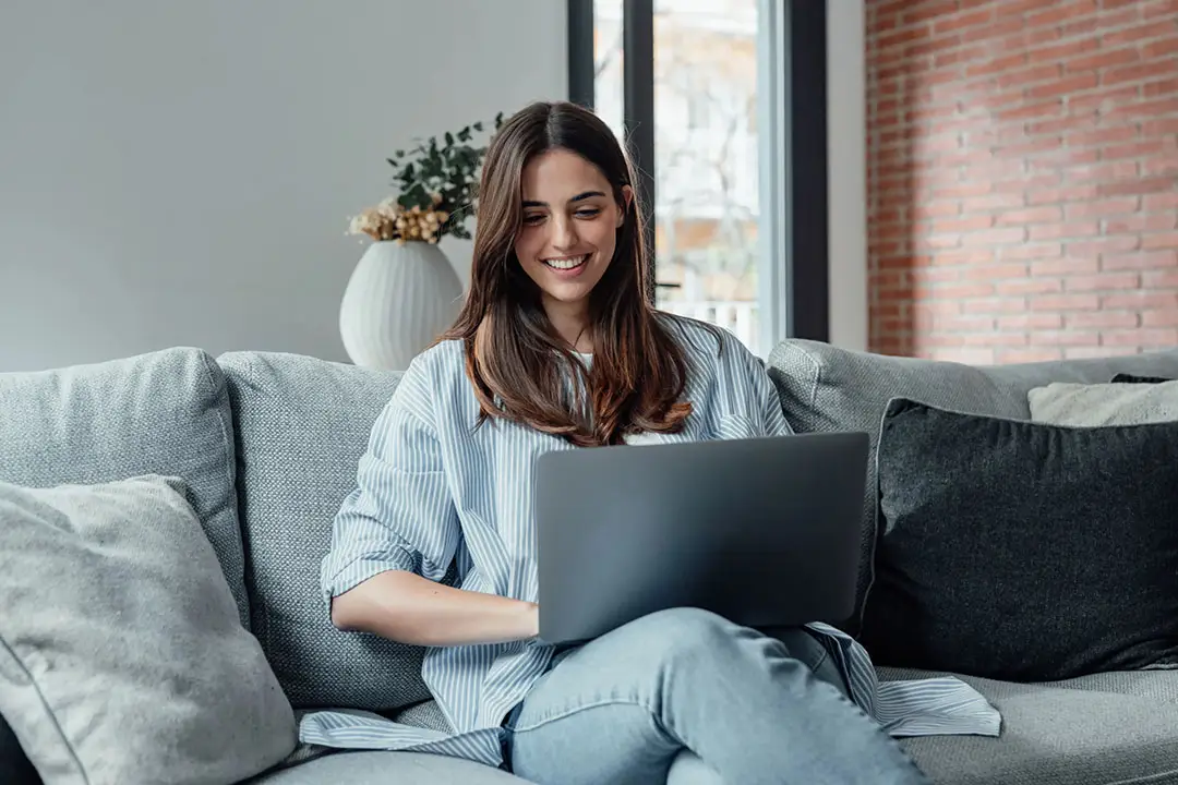 woman smiling at her laptopl while doing virtual iop from home scaled compressed,